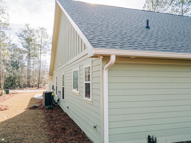 view of side of property featuring a shingled roof and cooling unit