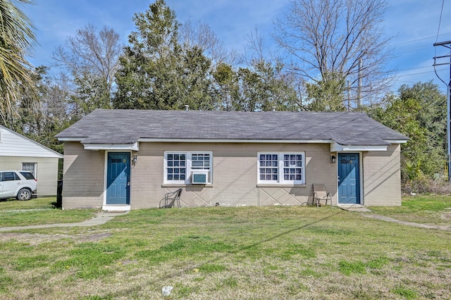 view of front of home with a front lawn, a shingled roof, cooling unit, and concrete block siding