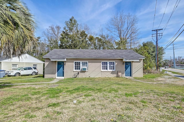 view of front of property with a shingled roof, concrete block siding, and a front yard