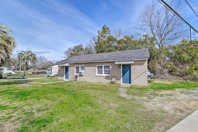 view of front of house with a front yard, a shingled roof, and concrete block siding