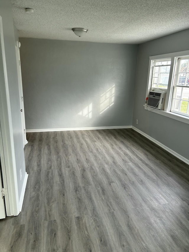 spare room with cooling unit, a textured ceiling, dark wood-type flooring, and baseboards