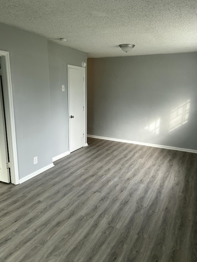 spare room featuring baseboards, a textured ceiling, and dark wood-style floors