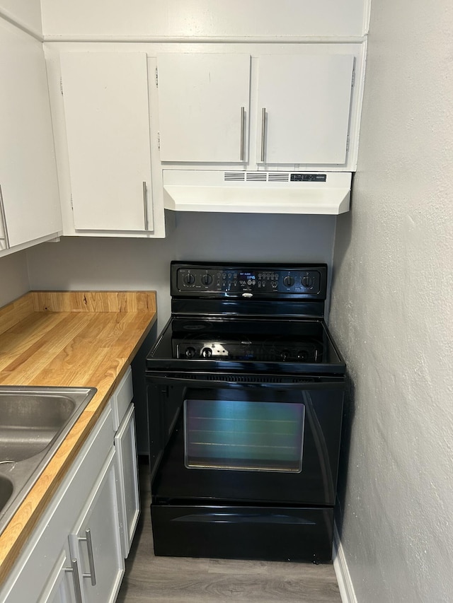 kitchen with wood finished floors, black range with electric stovetop, white cabinets, under cabinet range hood, and light countertops