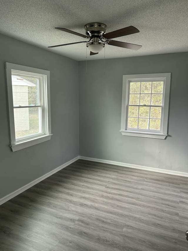 empty room with baseboards, ceiling fan, a textured ceiling, and wood finished floors
