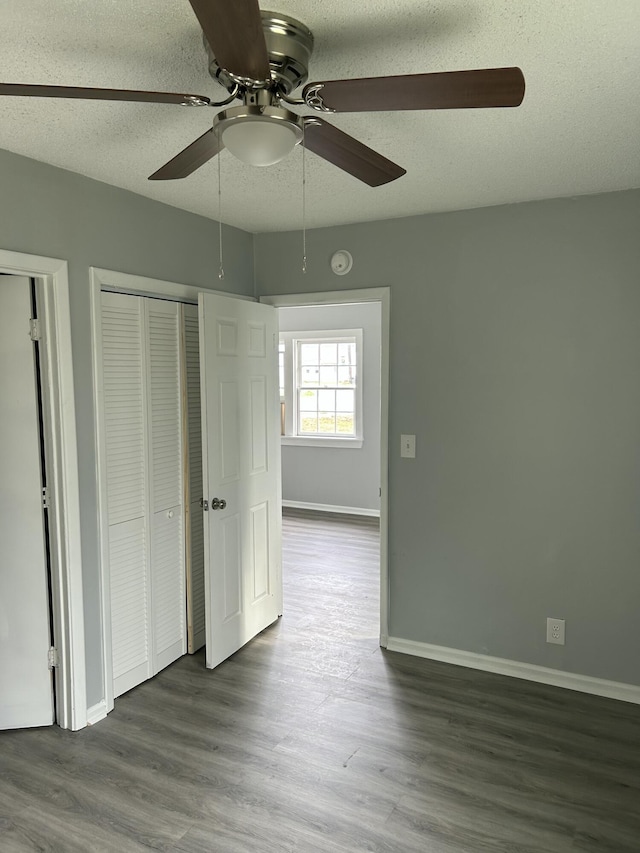 unfurnished bedroom with a textured ceiling, baseboards, and wood finished floors