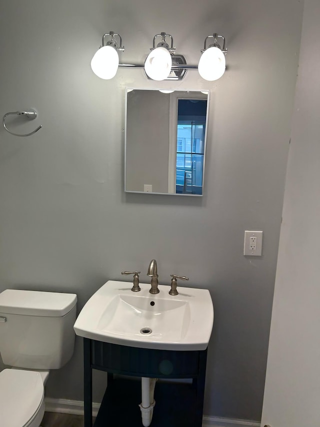 half bathroom with a sink, toilet, and baseboards