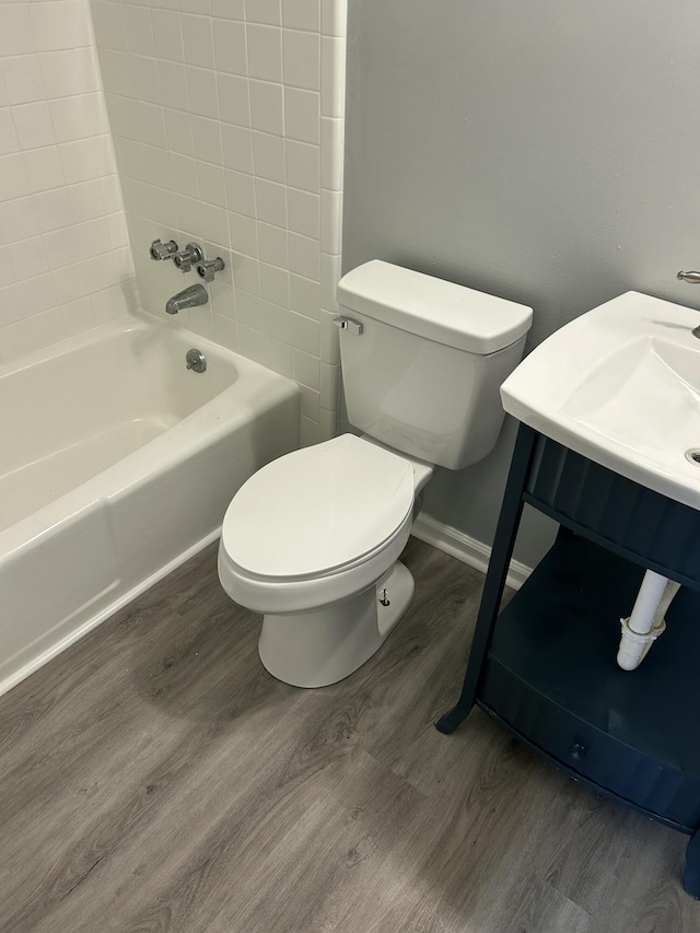 full bathroom with toilet, bathing tub / shower combination, wood finished floors, and baseboards