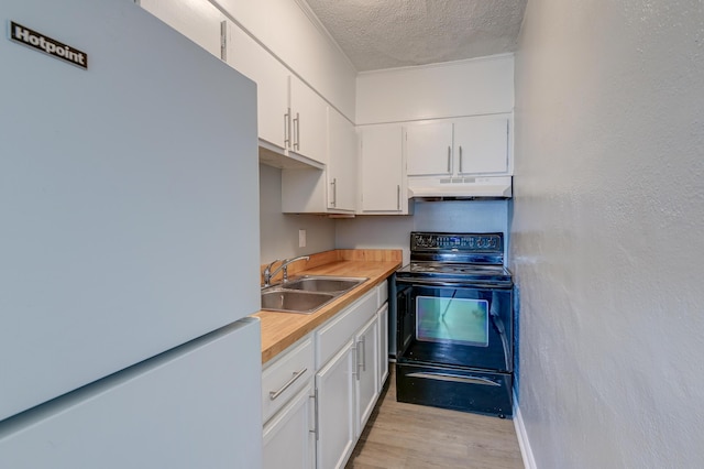 kitchen featuring a sink, freestanding refrigerator, under cabinet range hood, black range with electric stovetop, and light wood-style floors