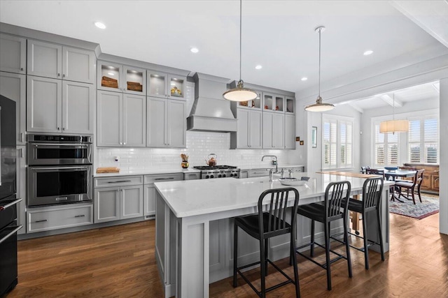 1962 Bellona St, Charleston, SC 29492 - kitchen with dark wood-style floors, custom exhaust hood, gray cabinets, double oven, and backsplash