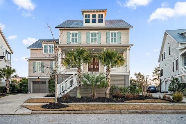 beach home featuring metal roof, an attached garage, covered porch, stairs, and concrete driveway