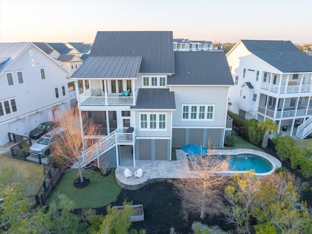1962 Bellona St, Charleston, SC 29492 - back of house at dusk featuring a standing seam roof, a patio area, metal roof, a balcony, and stairs