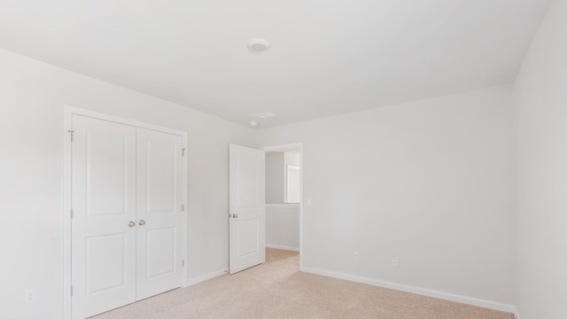 unfurnished bedroom with a closet and light colored carpet