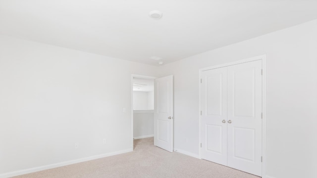 unfurnished bedroom featuring light carpet and a closet