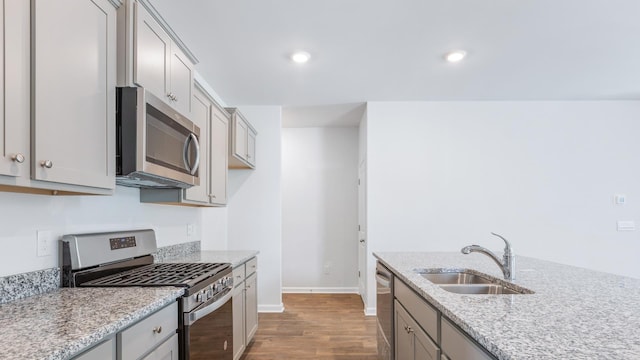 kitchen featuring gray cabinets, wood-type flooring, light stone counters, sink, and stainless steel appliances