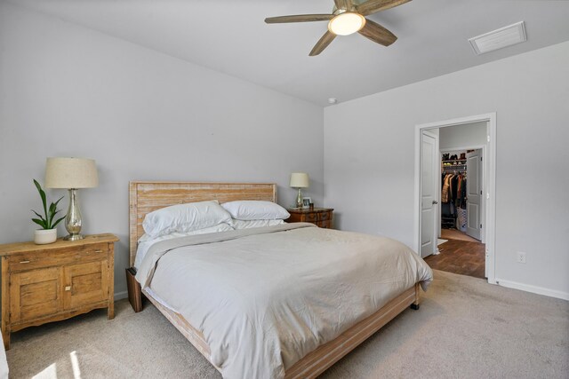 carpeted bedroom with a walk in closet, ceiling fan, and a closet