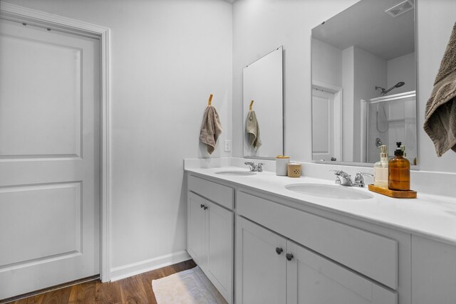 bathroom with hardwood / wood-style flooring, a shower with door, and vanity