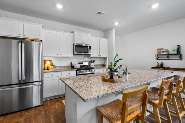 kitchen featuring appliances with stainless steel finishes, a kitchen island with sink, white cabinets, and dark hardwood / wood-style floors