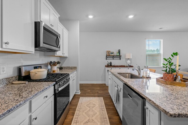 kitchen featuring backsplash, dark hardwood / wood-style floors, an island with sink, sink, and stainless steel appliances