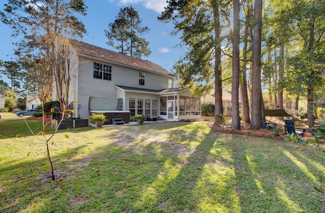 rear view of house featuring a sunroom, a lawn, and a hot tub