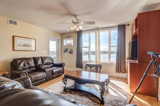 living room featuring ceiling fan, a textured ceiling, and a wealth of natural light