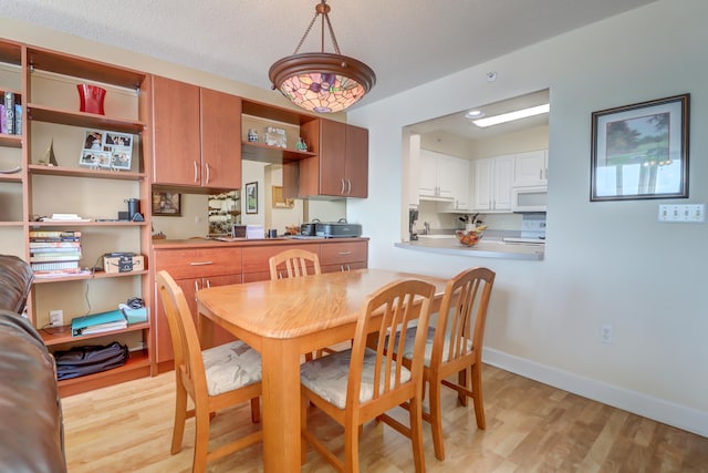 dining area with a textured ceiling and light hardwood / wood-style floors