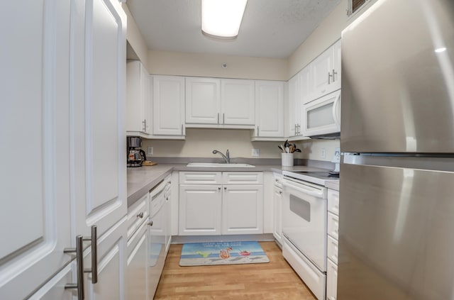 kitchen featuring white appliances, white cabinetry, sink, and light hardwood / wood-style flooring