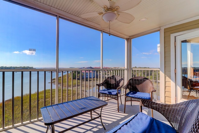 sunroom / solarium with ceiling fan and a water view