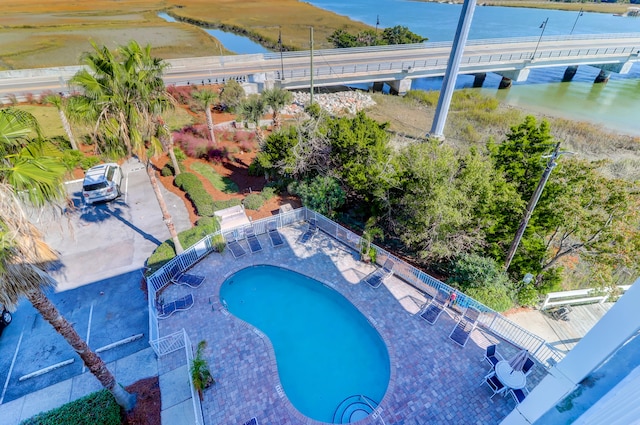 view of swimming pool featuring a patio and a water view