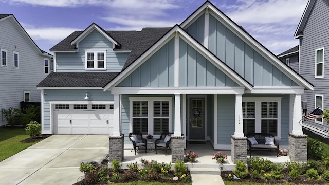 craftsman-style house featuring roof with shingles, board and batten siding, a porch, and concrete driveway
