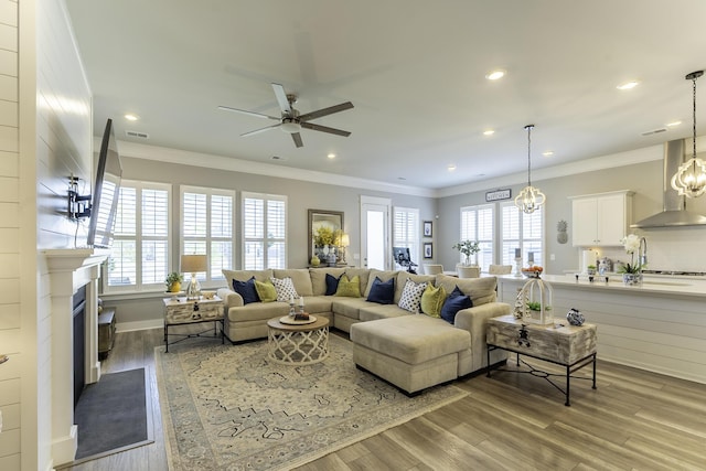 living area featuring ceiling fan, healthy amount of natural light, crown molding, wood finished floors, and recessed lighting