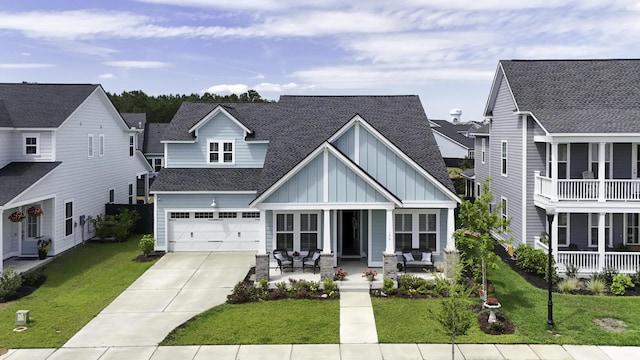 view of front of property with board and batten siding, driveway, covered porch, a garage, and a front yard