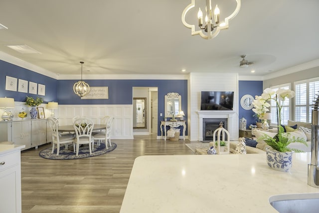 dining room featuring a chandelier, ornamental molding, a fireplace, wood finished floors, and recessed lighting