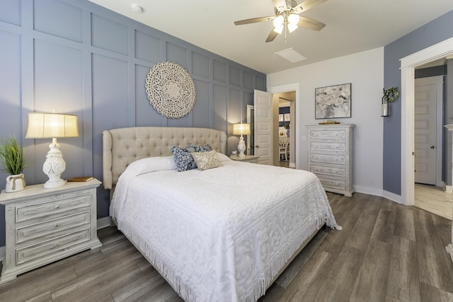 bedroom with dark wood-style flooring, baseboards, ceiling fan, and a decorative wall