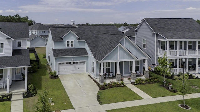 view of front of home with a porch, board and batten siding, driveway, a shingled roof, and a front lawn