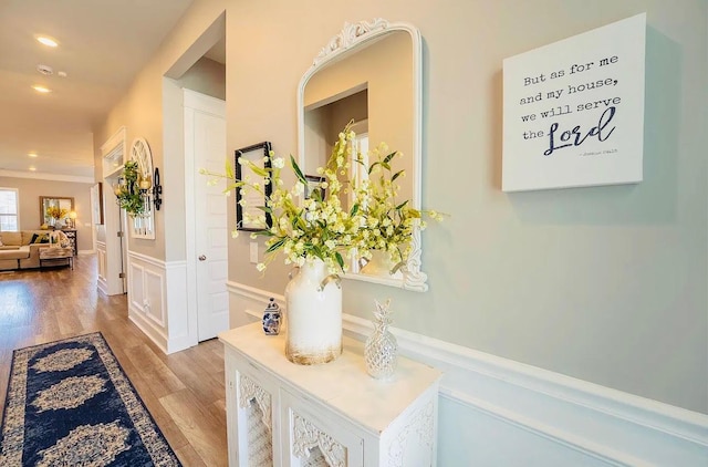 hall with light wood-type flooring, a wainscoted wall, recessed lighting, and a decorative wall