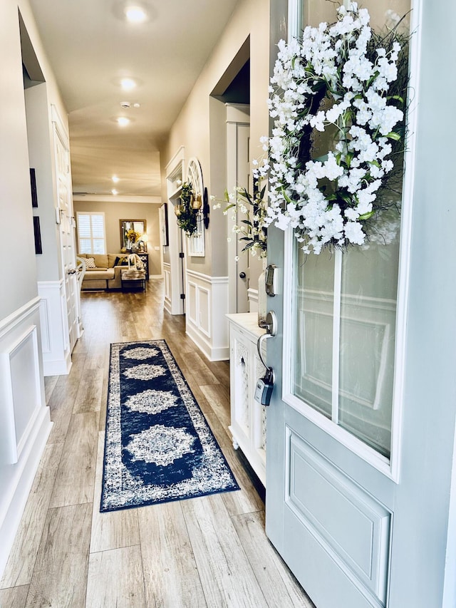 entryway featuring wainscoting, a decorative wall, and light wood-style flooring