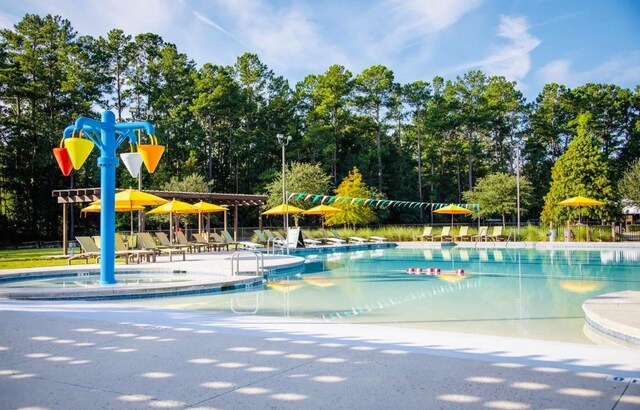 community pool featuring a patio area and view of scattered trees