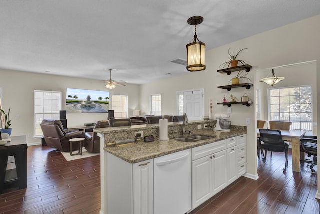 kitchen with light stone countertops, white cabinetry, sink, hanging light fixtures, and white dishwasher