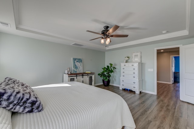 bedroom with wood-type flooring, a raised ceiling, ceiling fan, and ornamental molding