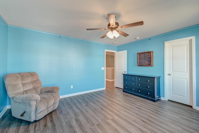 living area featuring ceiling fan, light wood-type flooring, and crown molding