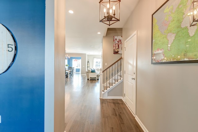 hall with hardwood / wood-style floors and an inviting chandelier