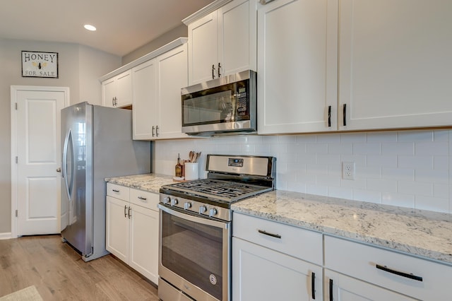 kitchen featuring white cabinets, appliances with stainless steel finishes, light hardwood / wood-style flooring, and light stone counters