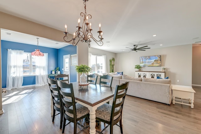 dining space with ceiling fan with notable chandelier and light wood-type flooring