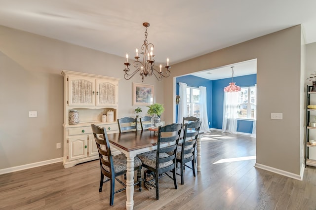 dining area with light hardwood / wood-style floors and a chandelier