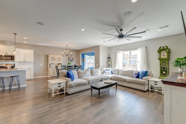 living room featuring ceiling fan with notable chandelier and light hardwood / wood-style floors