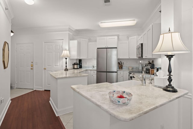 kitchen with crown molding, appliances with stainless steel finishes, a center island, white cabinets, and light tile patterned flooring