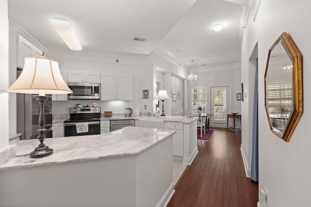 kitchen featuring ornamental molding, appliances with stainless steel finishes, white cabinets, and kitchen peninsula