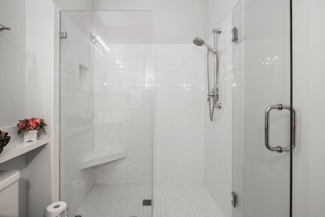 bathroom featuring toilet and a shower with shower door