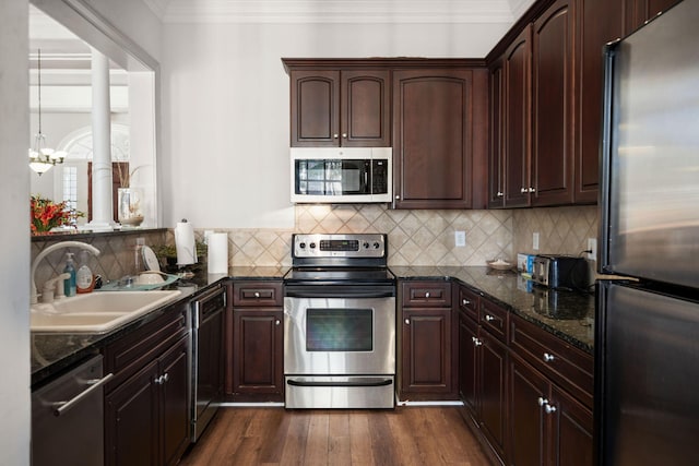 kitchen featuring sink, dark hardwood / wood-style flooring, dark stone counters, ornamental molding, and stainless steel appliances