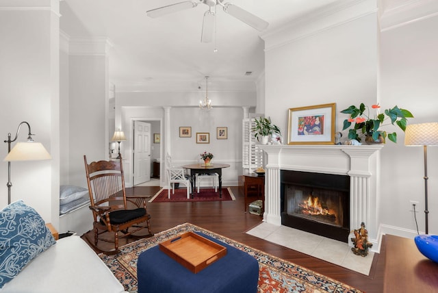 living room with crown molding, ceiling fan with notable chandelier, hardwood / wood-style floors, and decorative columns